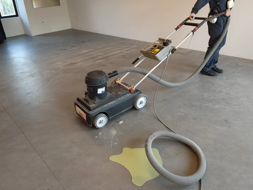 Een vloerfrees met stofafzuiging bewerkt een kale betonvloer
